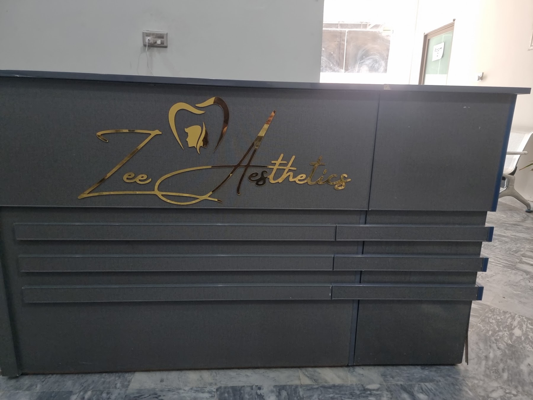 The gold Zee Aesthetics logo at the clinic reception